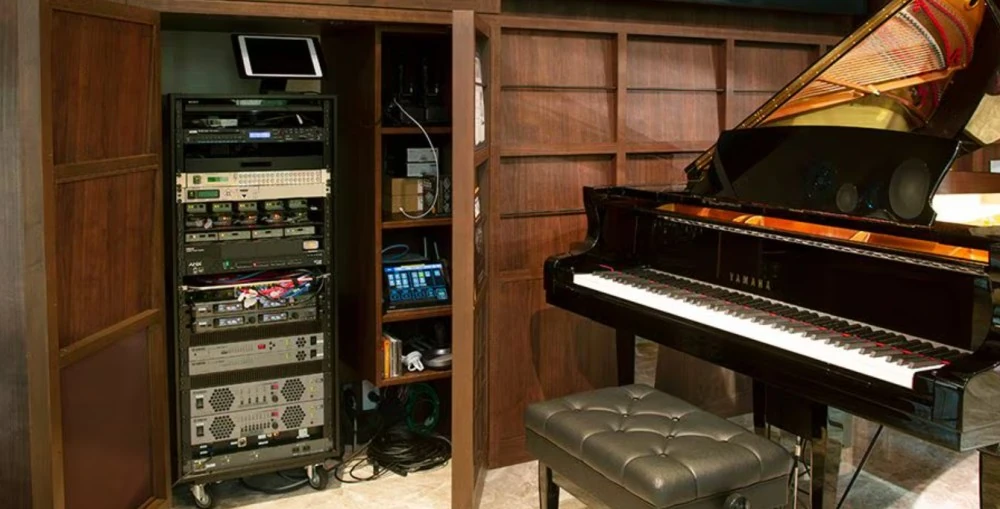 The audio equipment rack inside the front lobby wall cabinet alongside the Yamaha S6X-ENPRO Disklavier, which is prominent in the front lobby.
